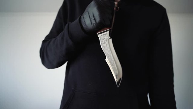 a man in black holds a sharp knife in his hands. Aggressive environment
