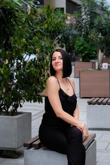 Naklejka premium Nice, brunette woman on a bench in the city. Smile, cute girl in Batumi, Georgia. Summer time.