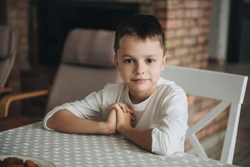 Family in a big house. Lifestyle Home comfort. Children at home. Beautiful kitchen. Portrait of a boy at the table. Waiting for dinner. Children's diet. Baby food.