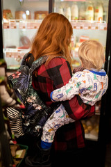 A mother holds a baby in her arms at a grocery store.