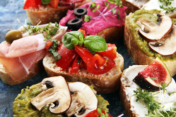 Assorted bruschetta with various toppings. Appetizing bruschetta or crudo crostini. Variety of small sandwiches. Mix bruschetta with tomatoes and basil