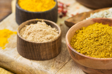 Spices in wooden bowls on a wooden table. Turmeric, ginger and curry in wooden bowls. Close up