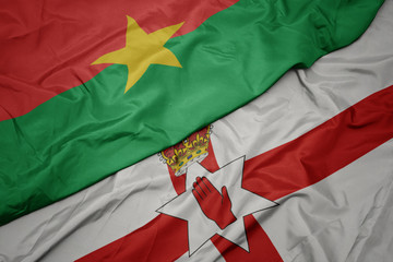 waving colorful flag of northern ireland and national flag of burkina faso.