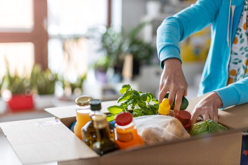 Young woman unpacking boxes of food at home
