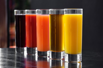 Orange, Apple, tomato, carrot, cherry juice in glass glasses on a black background with apples, grapefruit and mint