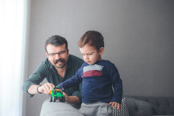 Cheerful father plays with toddler with his toys