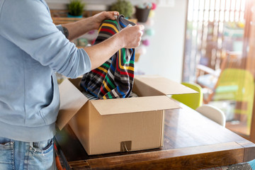 Man at home unpacking parcel with clothing
