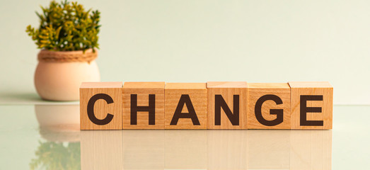Word CHANGE is made of wooden building blocks lying on the table and on a light grey background....