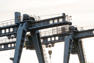Naklejka premium two large bridge cranes on the background of the sky at sunset. Outline of a girder crane on a cloud background. overhead cranes