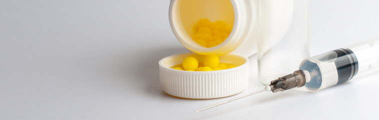 Round yellow vitamins are poured out on a white glossy table from a white plastic bottle. Concept. Place for the label. Diagnosis.
