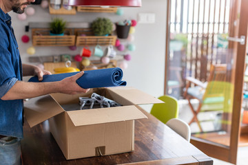 Man unpacking box with workout equipment at home
