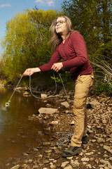 Man exploring river water by magnet on rope