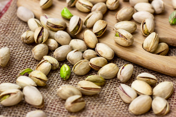Roasted salted pistachio nuts in nutshell on wooden board background.