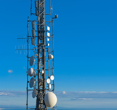Telecommunications tower, antenna and satellite dish, 5G network repeaters, base transceiver station and blue sky as background. Copy space.
