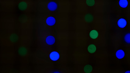 Blur Christmas vertical lights - green and blue on the black background in the darkness. Macro shooting