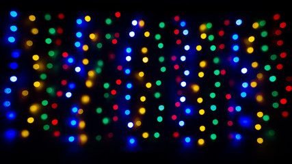 Blur Christmas vertical lights - yellow, red, green, blue on the black background in the darkness 