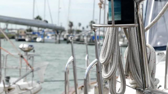 Ropes and other rigging of a sail boat docked in a marina. Selective focus shift with shallow depth of field in handheld clip.