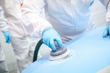 A professional mechanic paints a car in a workshop