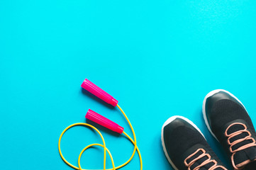 Skipping rope and sports shoes on blue background. Minimalist fitness concept. Top view and copy space flat lay.