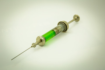 vintage syringe with green vaccine in the style of steam punk in perspective