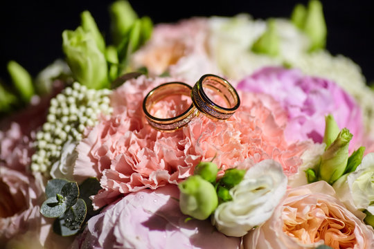 Wedding rings made of metal lie on a beautiful bouquet of fresh flowers.