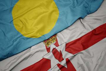 waving colorful flag of northern ireland and national flag of Palau .