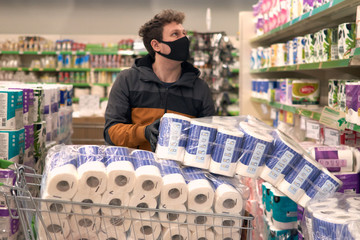 Man in disposable medical face mask and gloves buying in supermarket. Panic shopping during Coronavirus covid-19 pandemic.