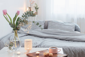 interior of bedroom with flowers, candles and cup of tea