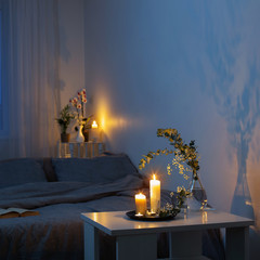 night interior of bedroom with flowers and burning candles