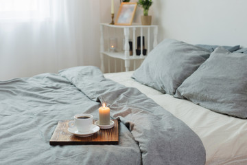burning candle and cup of coffee  in white bedroom