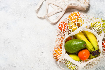 Mesh bag with fruits on white background.