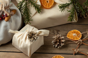 Obraz na płótnie Canvas Zero waste christmas concept. Packed in natural fabric gifts and decorations from natural materials on a wooden table