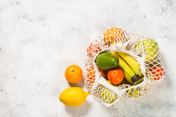 Mesh bag with fruits on white background.