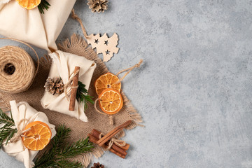 Zero waste christmas concept. Packed in natural fabric gifts and decorations from natural materials on gray table, top view, copy space