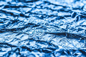 Fototapeta premium blue background of crumpled foil. shiny metal foil as a blue background or texture