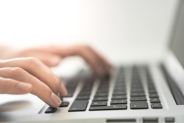 Hands writing on a Keyboard of a Laptop or Notebook in Home Office