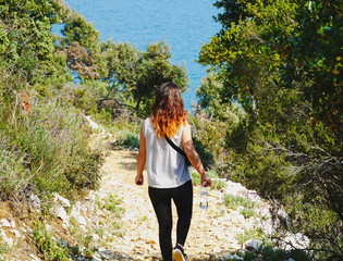 Naklejka na ściany i meble Woman hiking in picturesque nature in a forest by the sea