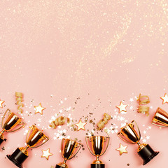 Winner cups with confetti and festive stars on a pastel background with copy space on top. Flat lay...