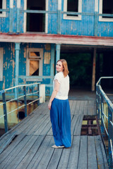 woman in stand old bridge, destroyed buildings.