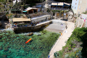 Fototapeta na wymiar Kolorina beach just outside the walls of Dubrovnik in Croatia - Orange kayak in turquoise waters in the Adriatic Sea