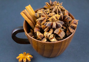 A cup, filled with spices, close-up on blue background.
