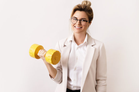 Happy successful business woman is lifting heavy dumbbell