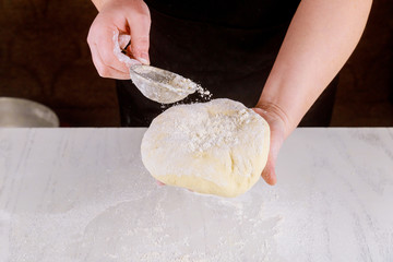 Raw pizza dough in hands of person.