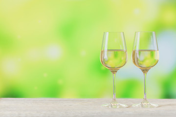 Two glasses of white wine on light green background. Wine mood concept