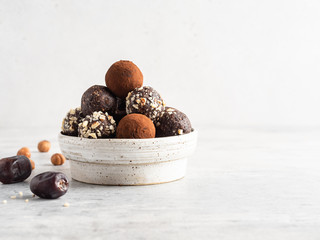 Energy balls. Healthy raw dessert (bliss balls), vegetarian truffles, sugar free candies made of dates, hazelnuts, cocoa powder. White wooden background.  Copy space