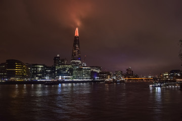 Naklejka premium London and the Thames river at night, long exposure photography with the big tower painting the sky in orange