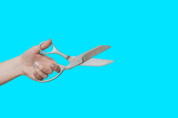 Old scissors. Rare scissors in a hand. Female hand holds scissors.Isolate on a blue background.