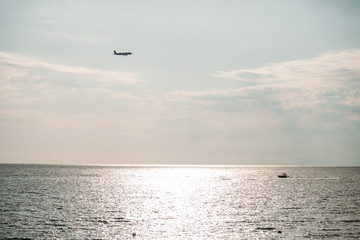 the plane in the sky over the sea on a summer day.
