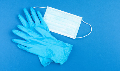 Medical gloves and mask on blue background. 