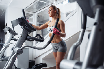 Fit young woman doing cardio on the xtrainer machine in gym. Fat burn. Health concept. Weight loss.